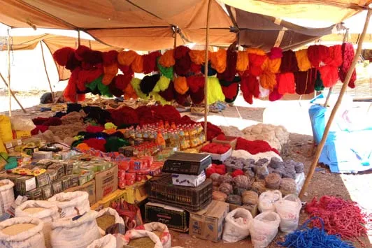 Open-air market stall displaying bags of brightly coloured dye powders