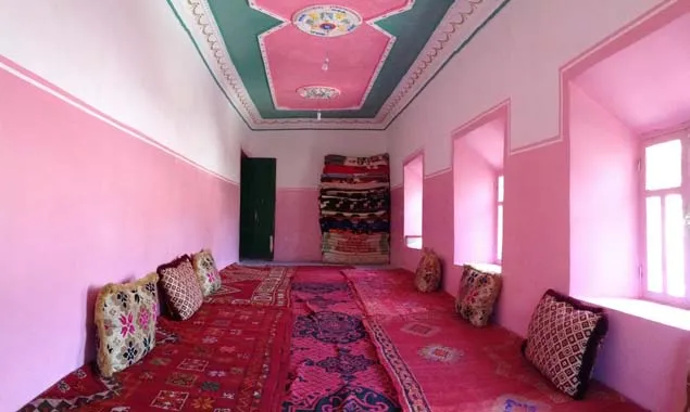 Pink interior with rugs and cushions arranged around the walls