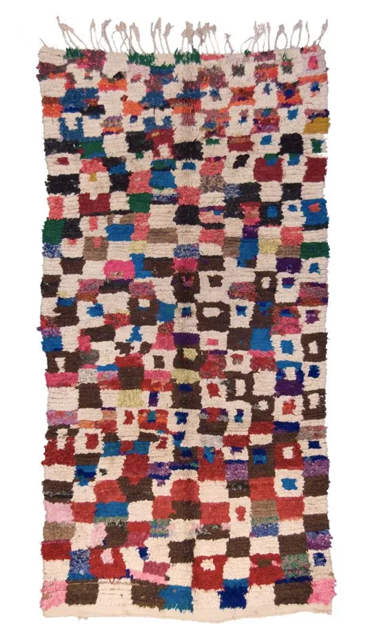 Patchwork-like rug composed of small red, blue, black and white blocks
