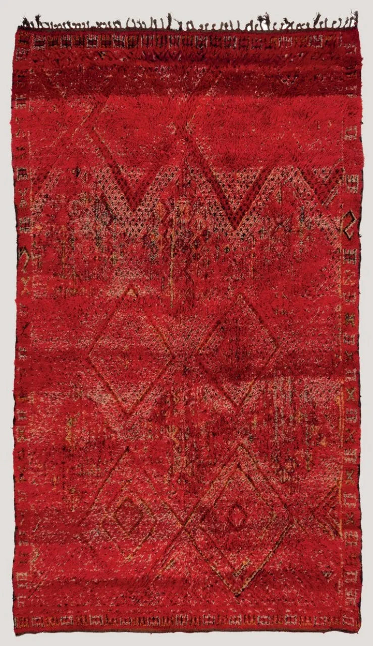 Front of a red Zayan rug by a female master weaver