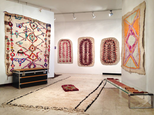 a very unusual rug from the Ourika valley on the left wall, an unusual minimal Beni Ouarain rug + a Boujad pillow on the floor, three turkmen felt prayer rugs on the back wall, another Afghan felt rug on the right wall
