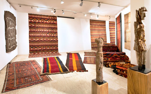 l > r: (walls)Baluch felt rug, Uzbek kilims, 'djulchir' sleeping rugs / (floor) Baluch rug, 'djulchir' sleeping rugs, piles of central Asian kilims, sculptures from Timor + Borneo